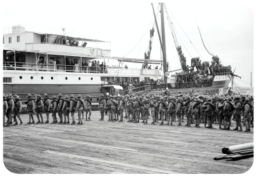 World War II soldiers stand near a battleship preparing to board