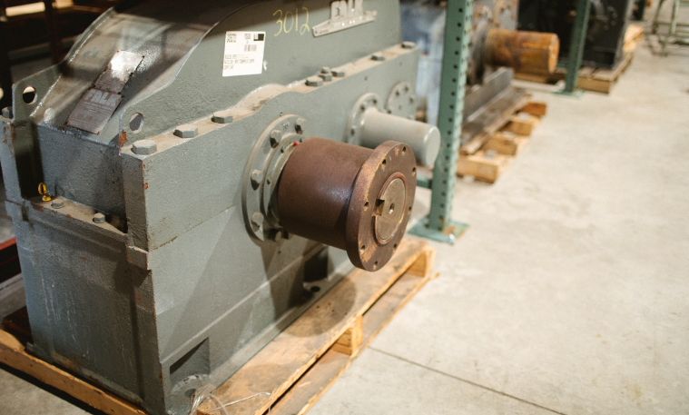 A large industrial gear reducer sits in a warehouse