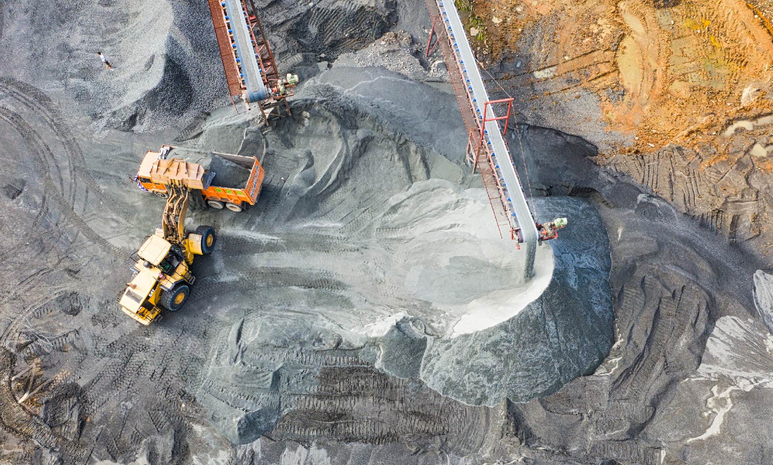 A mining operation is using a conveyor belt to remove rocks and sand .