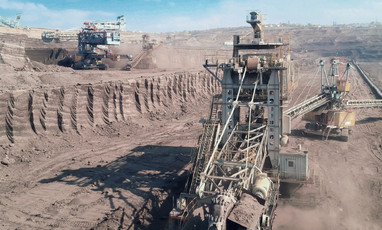 Open pit mining operation using industrial equipment, cranes, and conveyor belts.