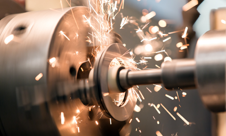 Sparks fly from an industrial gearbox being used in manufacturing equipment.