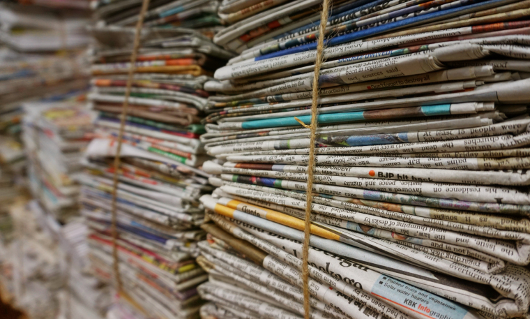 Giant stacks of newspapers are bound with twine and kept in a warehouse.