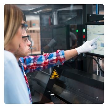 Man and woman working on a touch-screen computer at a manufacturing facility.